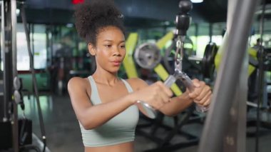 Genç ve güzel Afrikalı Amerikalı sporcu kadın spor salonunda egzersiz yapıyor. Spor giyinen çekici aktif atlet kız sağlık hizmetleri ve spor salonunda kas geliştirmek için halterleri kaldırarak spor yapıyor..
