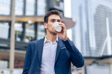 Kafkasyalı genç işadamı şehirde yürürken akıllı telefondan konuşur. Çekici yakışıklı erkek çalışan kulaklık takıyor ve dışarıda iş arkadaşlarıyla güvenli bir şekilde iletişim kuruyor..