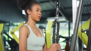 Kadın spor salonunda kablo makinesiyle egzersiz yapıyor.