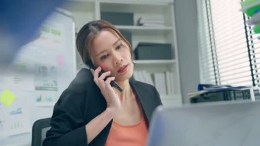 İş kadını ofiste telefonla konuşuyor.