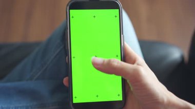 Elinde yeşil ekranlı akıllı telefon tutan kişi