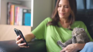Elinde kedisiyle akıllı telefon tutan kadın.
