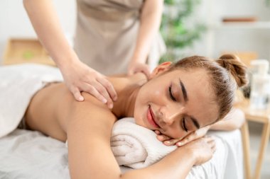 Güzel bir kadın güzellik merkezinde sırt masajı yaptırıyor. Çekici genç kız masaj yatağında uzanıp masaj kliniğinde vücut için masözden rahatlatıcı fizyoterapi hizmeti alıyor..