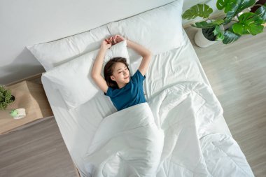 Pijamalı Asyalı güzel kız sabah mutlu bir yüzle uyanır. Çekici genç bir kadın kendini rahatlamış hisseder ve uyumaktan zevk alır. Yatak odasında, yatak odasında yataktan kalkar. Sağlık Sağlığı Konsepti.