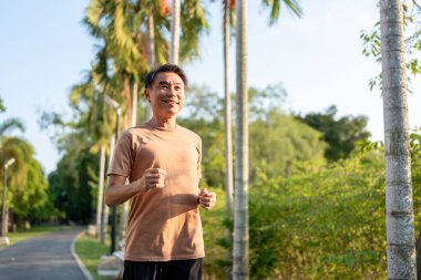 Asyalı yaşlı sporcu dışarıda bahçede egzersiz yapıyor. Çekici olgun yaşlı erkek koşucu mutlu ve rahat hisset, gün batımında halk parkında sağlık hizmetleri için alıştırma yap..