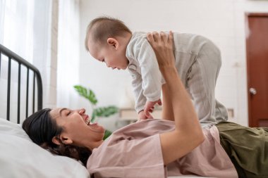 Asyalı bir anne kucağında bebeğini nazikçe yatak odasına atar. Çekici güzel anne, sıcak ve sevgi dolu bir aile ortamını besleyerek, yeni doğmuş bebekle rahat bir odada oynayarak hassas bir anı paylaşıyor..