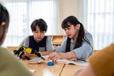 İlkokulda robotik dersinde öğrenen bir grup öğrenci. Hevesli genç öğrenciler masada oturup öğretmenlerinin sınıfta robotik dersi vermesini dinliyorlar..