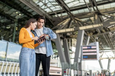 Havaalanı terminalinin dışında kaybolmuş gibi görünen Asyalı genç bir çift. Çekici erkek ve kadın arkadaşlar tatil gezisi için uçakla yurtdışına gittikleri için mutlu ve heyecanlı hissediyorlar..