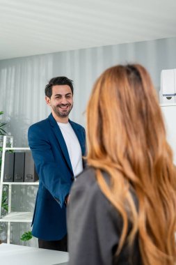 Beyaz iş adamı ve iş kadını ofiste tokalaşıyor. Şirket işyerinde birlikte duran meslektaşlar, iş anlaşması görüşmeleri sonrasında ortaklık anlaşmasının tadını çıkarırlar.