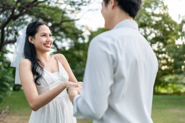 Asyalı romantik evli çift gün batımında parkta birbirine bakıyor. Çekici genç damat ve gelin aşklarını kutluyor ve Sevgililer Günü 'nü dışarıda düğün öncesi fotoğraf çekimlerinin keyfini çıkarıyorlar..