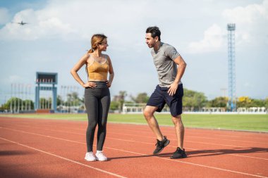 Stadyumda birlikte egzersiz yapan çeşitli genç erkek ve kadın sporcular. Çekici sporcu ve erkek antrenör ısınıyor ve antrenman yapıyor. Antrenman sırasında yapılacak yarışmaya hazırlanın.
