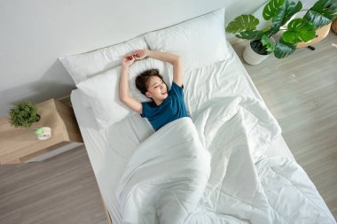 Pijamalı Asyalı güzel kız sabah mutlu bir yüzle uyanır. Çekici genç bir kadın kendini rahatlamış hisseder ve uyumaktan zevk alır. Yatak odasında, yatak odasında yataktan kalkar. Sağlık Sağlığı Konsepti.