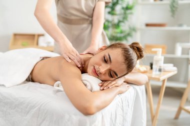 Güzel bir kadın güzellik merkezinde sırt masajı yaptırıyor. Çekici genç kız masaj yatağında uzanıp masaj kliniğinde vücut için masözden rahatlatıcı fizyoterapi hizmeti alıyor..