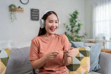 Asyalı kadın evdeki kanepede otururken müzik ve dans dinler. Çekici genç kız kulaklığını taktı, mutlu hissetti ve hafta sonu tatillerinde evde vakit geçirdi..