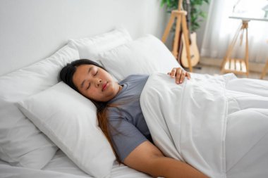 Sabahları pijamalı Asyalı kadın mutluluktan uyuyor. Çekici, genç, kıvrımlı dişiler mutlu ve rahatlar. Boş vakitlerini yatakta uzanıp evdeki rahat yatak odasında dinlenerek geçirirler..