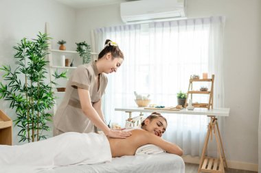 Güzel bir kadın güzellik merkezinde sırt masajı yaptırıyor. Çekici genç kız masaj yatağında uzanıp masaj kliniğinde vücut için masözden rahatlatıcı fizyoterapi hizmeti alıyor..