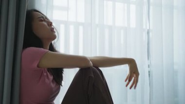 Rahatlamış bir ifadeyle pencerenin yanında oturan kadın