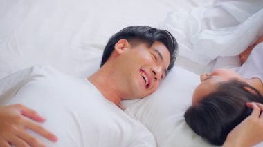 Yatakta birlikte uzanan gülümseyen çift.