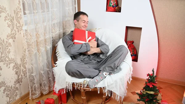 Een Man Knuffelt Een Nieuwjaarscadeau Met Een Glimlach Zijn Gezicht — Stockfoto