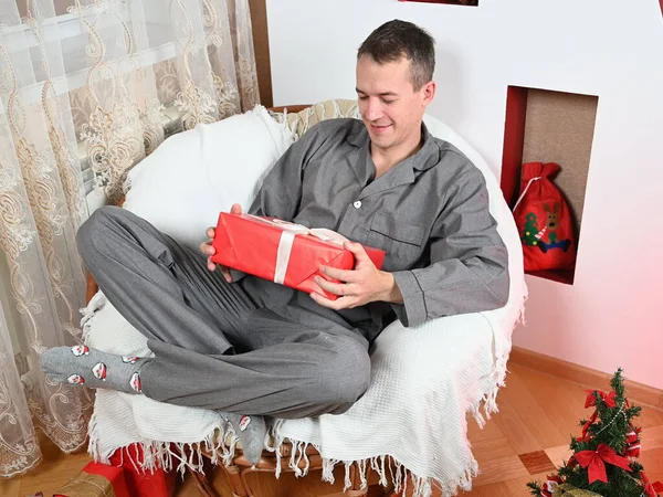 Ein Mann Einem Stuhl Mit Einem Neujahrsgeschenk Hochwertiges Foto — Stockfoto