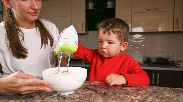 Mother and child stir the dough with a mixer. High quality photo