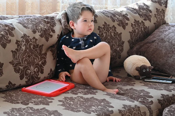 孩子一个人坐在沙发上看电视 高质量的照片 — 图库照片