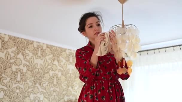 Young girl rub the chandelier from dust. House cleaning — Stock Video