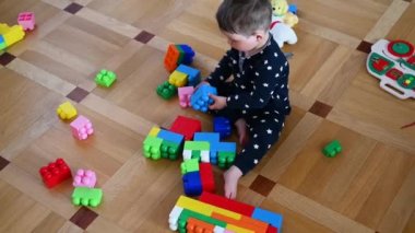 Yerde oturan renkli bir inşaatçının içinde bir çocuk oynuyor..