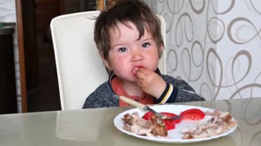 Çocuk bir sandalyeye oturup yemek yiyor. 1-2 yaşındaki bir çocuğun öğle yemeği.