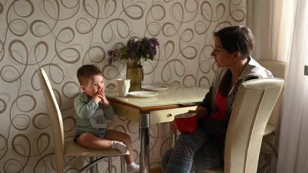 Mamá con un niño están sentados en la cocina — Vídeo de stock