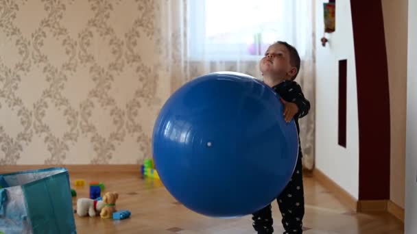 Çocuk büyük mavi bir topla oynuyor. Motor becerilerini geliştiriyor. Bebek oyunu — Stok video