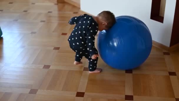 Küçük bir çocuk bir topla oynuyor. Bebek kafasını topa vuruyor. — Stok video