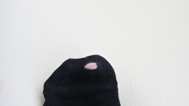 Roztrhaná černá ponožka. Unikající černá ponožka na izolovaném pozadí. — Stock video