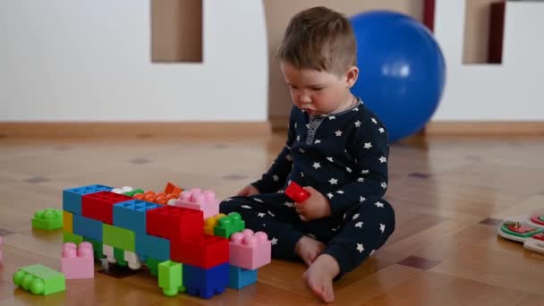 Das Kind spielt in der Nähe des Konstrukteurs. 1-2 Jahre altes Baby — Stockvideo