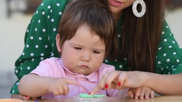 Joven madre juega en la mesa con su hijo en plastilina — Vídeo de stock