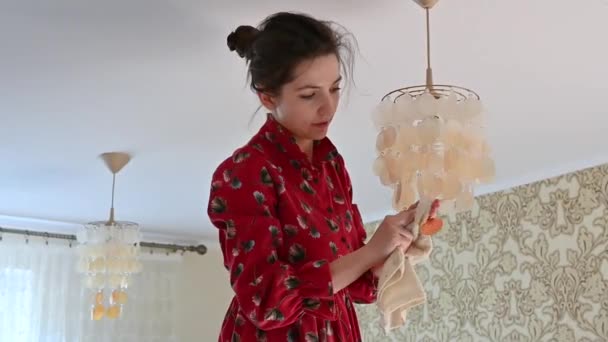 La jeune fille frotte le lustre de la poussière. Nettoyage de maison — Video