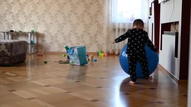 Un niño pequeño está jugando con una pelota. Bebé golpeando su cabeza en una pelota — Vídeo de stock