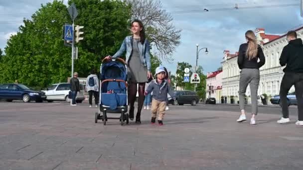 Een kind met moeder en een wandelwagen door de stad — Stockvideo