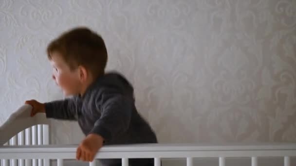 Chlapeček se baví v postýlce a usmívá se do kamery — Stock video