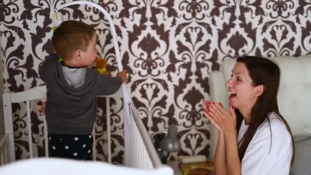 Bebé con madre divirtiéndose en la cuna en casa — Vídeo de stock