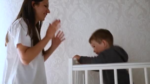 Mamma con bambino che si diverte nella nursery. Il bambino nella culla — Video Stock