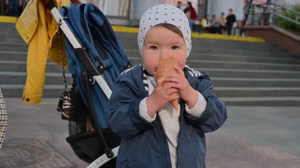 1-2 year old child eats ice cream on the street. stroller background — Wideo stockowe