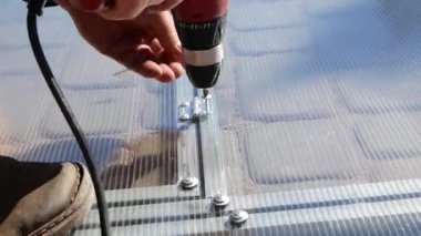 Adam polikarbonatta vidaları sıkıyor.