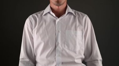 Beyaz gömlekli bir adam teslim olmak için ellerini kaldırıyor. koyu bir arkaplanda