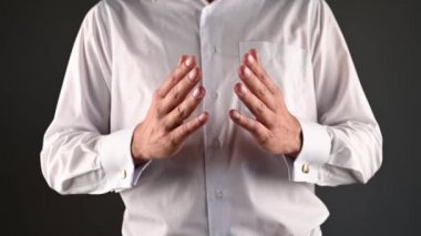 Beyaz gömlekli bir adam ellerini kullanarak yardım eder.