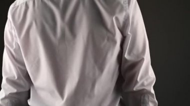 Beyaz gömlekli bir adam aynanın önünde caka satıyor. koyu bir arkaplanda