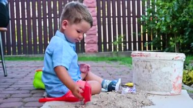 Küçük çocuk sokakta bir teknede oynuyor.