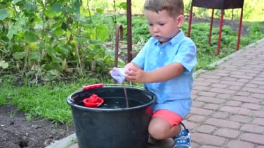 Küçük çocuk sokakta bir teknede oynuyor.