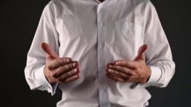 Beyaz gömlekli bir adam elleriyle sohbet eder. koyu bir arkaplanda