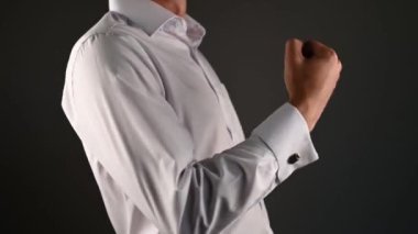 Bir adam önde bir yumruk tutuyor. Takım elbiseli bir adam ileri bir kuak gösterir.